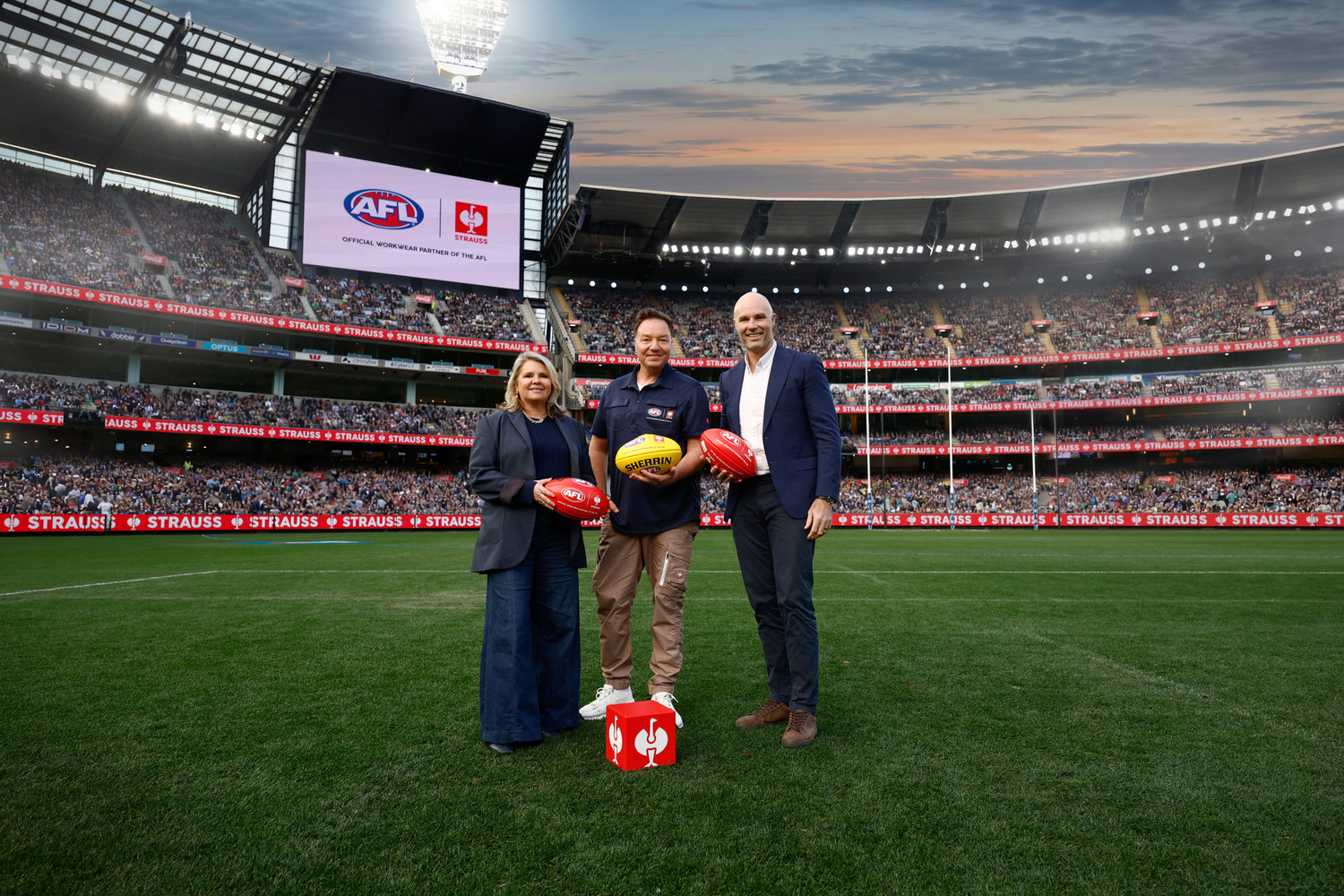 Three people standing an AFL stadium